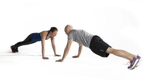 couple face each other in plank pose