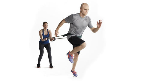 couple works out doing sprints with rubber resistance tubing
