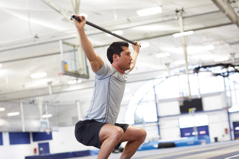 Man does squat with bar lifted above head