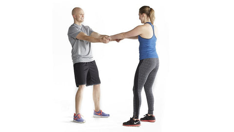 couple interlace hands preparing to squat facing each other