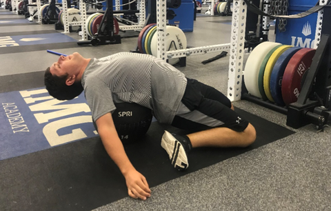 Man at the gym by laying back across a SPRI Soft Shell Med Ball
