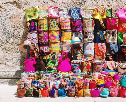 colorful wayuu mochila bags from colombia against a wall