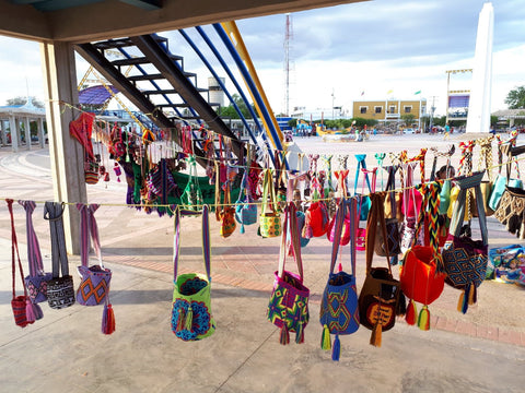 wayuu mohcila bags hung on strings in an artisan market in uribia's town square