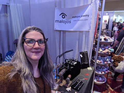 Natalia standing next to her booth at Vogue Knitting Live NYC 2020