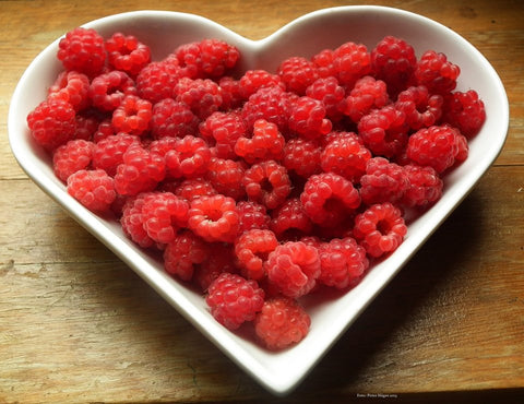 Heart shaped bowl full of raspberries