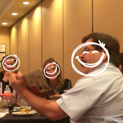 People around a table holding books with smiley faces