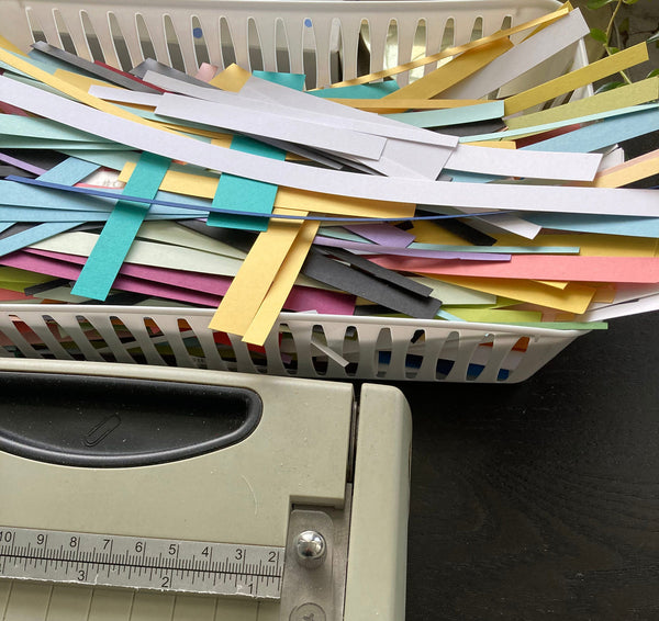 basket of paper scraps next to a paper trimmer