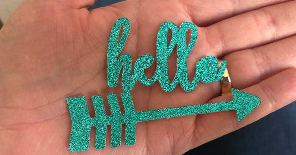 hand holding hello and arrow cut from glitter paper 