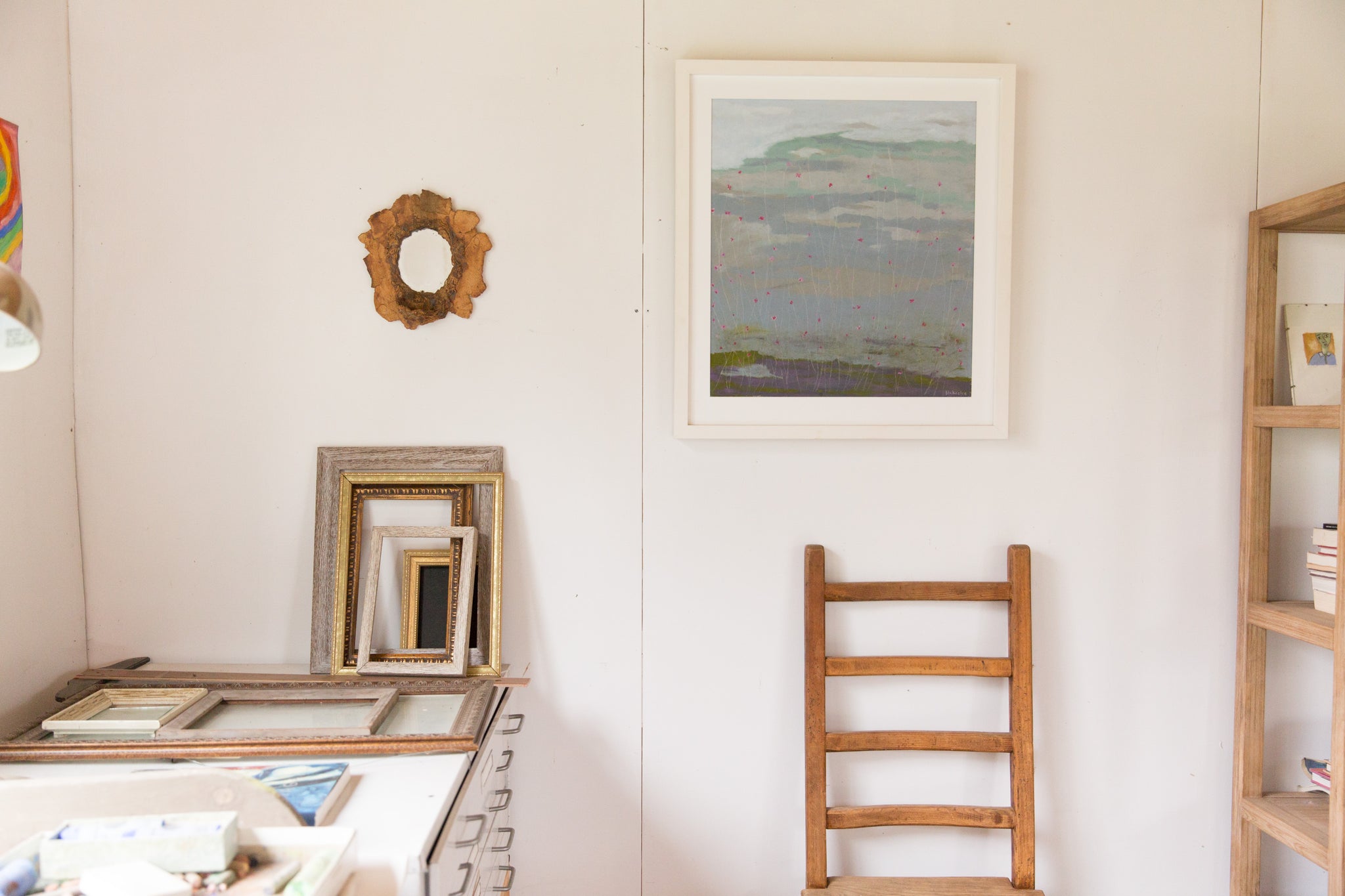 framed pastel artwork above wooden chair