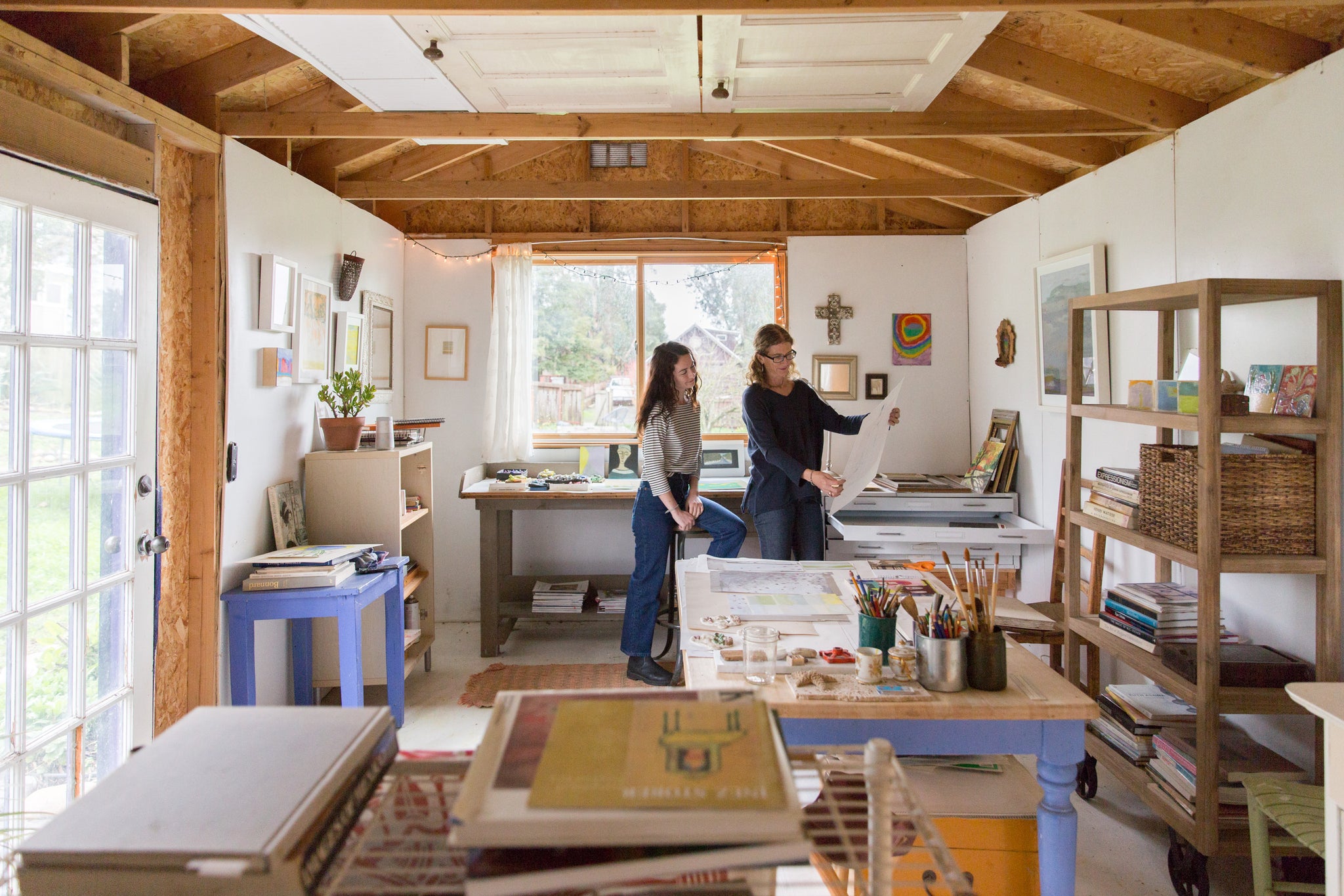 artist, Kate Blakeslee, showing artwork to daughter, Cecilia Payne, in wide shot of studio