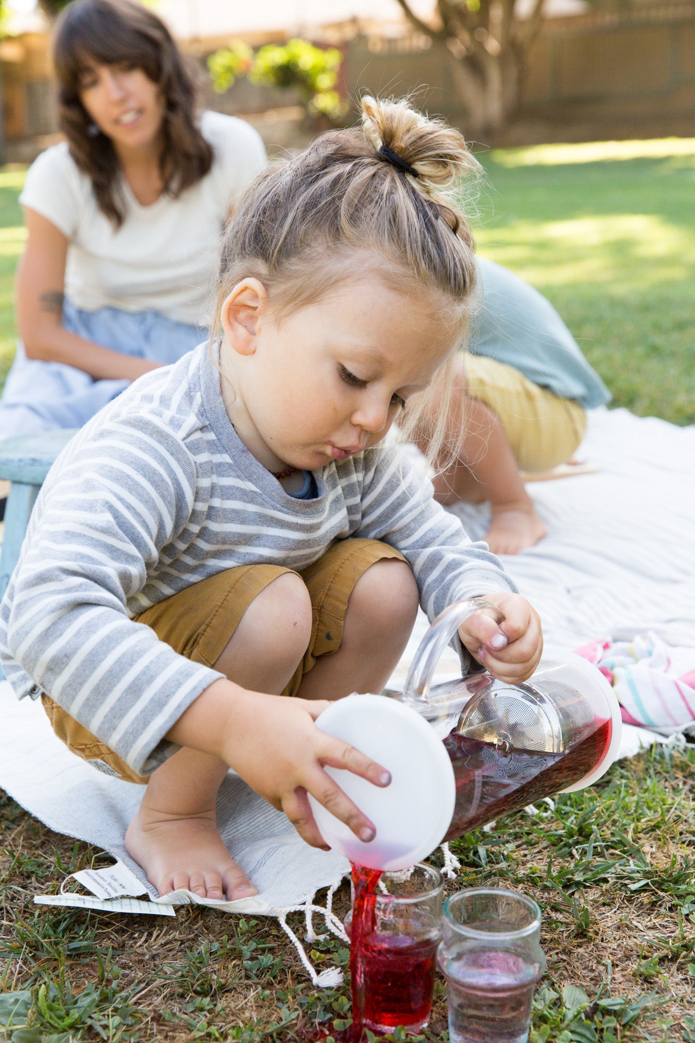 toddler pouring loosing leaf tea with glass tea jug