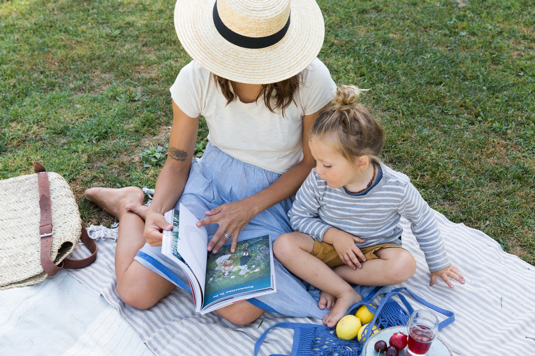 mom and son reading "Early Riser Companion" in injiri skirt with woven hat