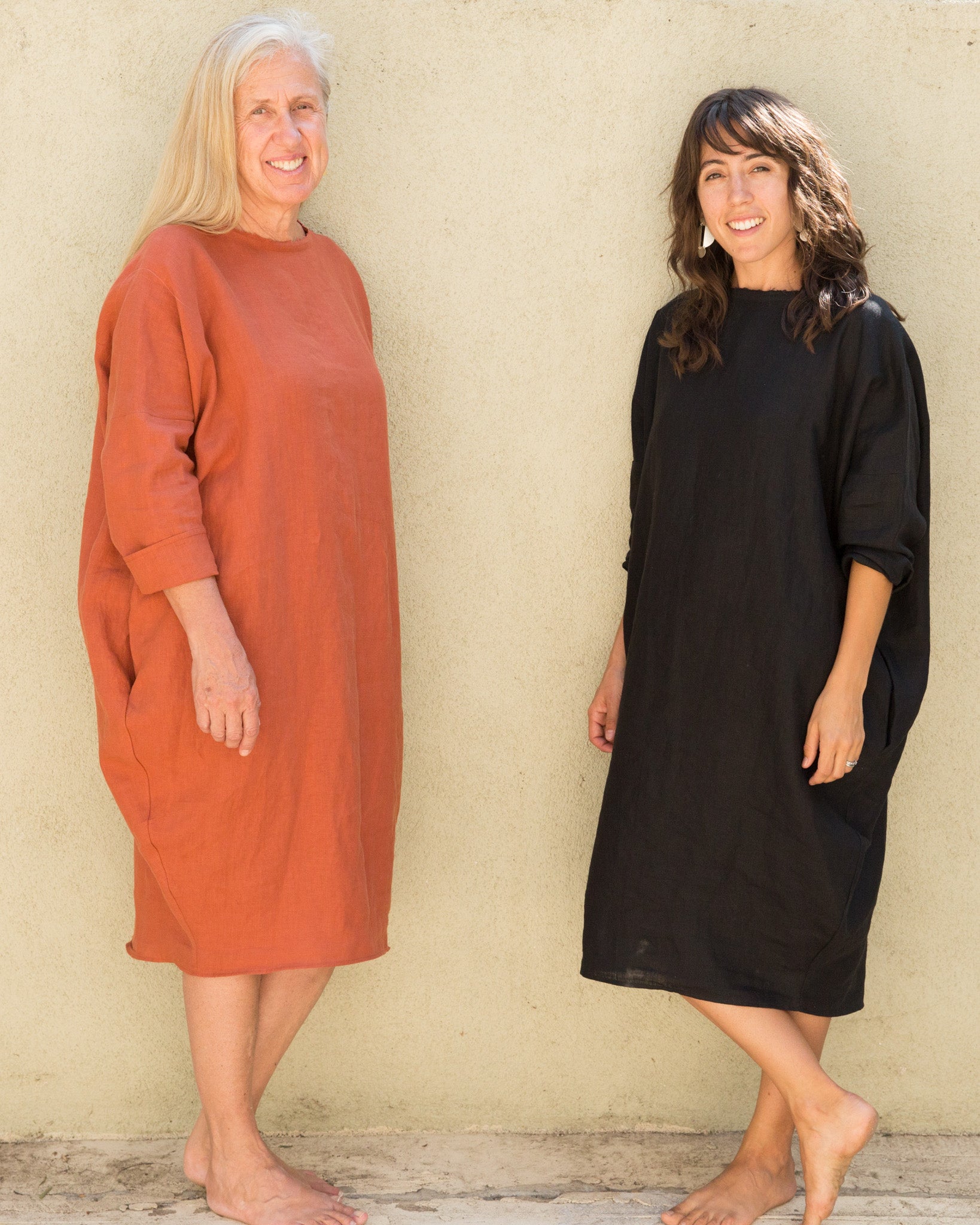 Dotter owners, Susanne McLean and Annika Huston, wearing Robyn King dresses in front of green wall