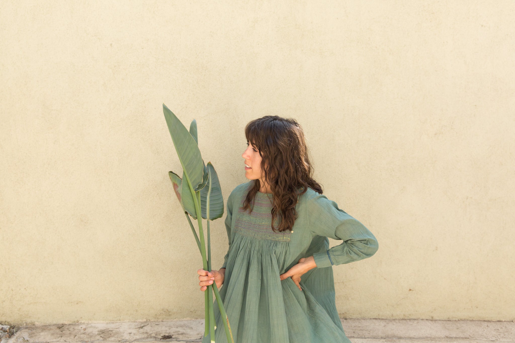 Dotter owner, Annika Huston, holding plant branches in front of green wall