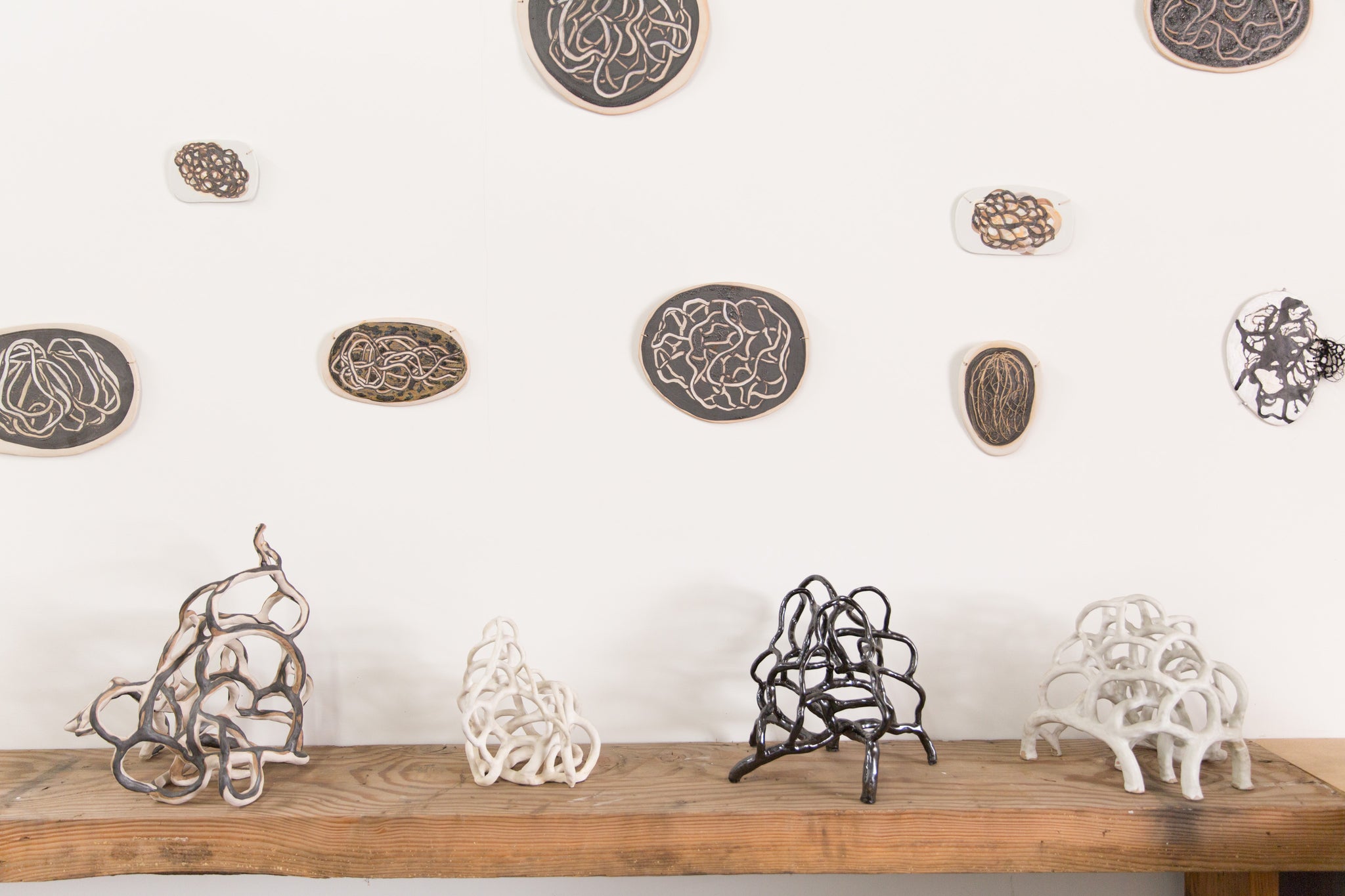 ceramic artworks by Laura Cooper hung on wall and on standing on table