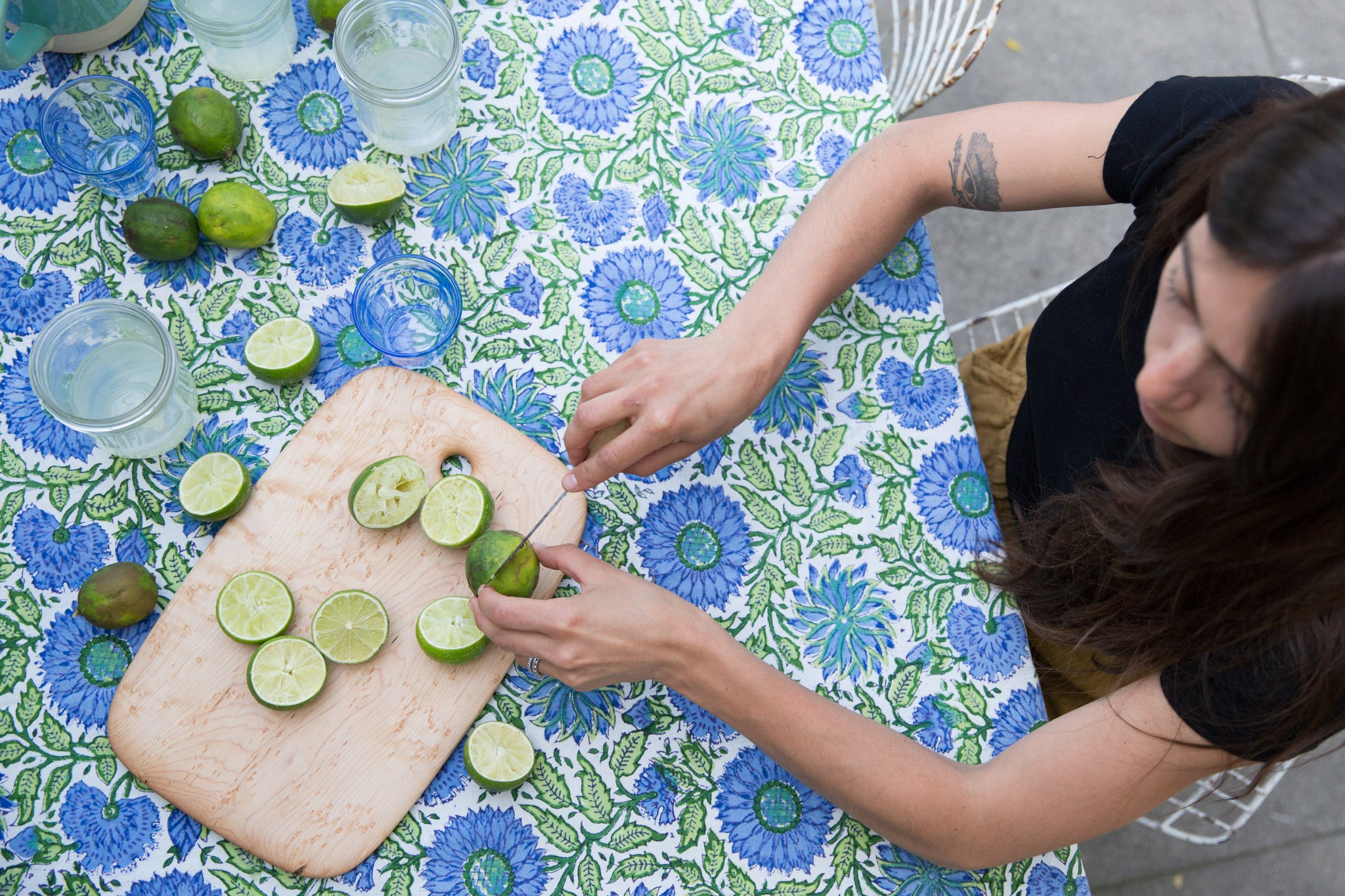 Dotter owner, Annika Huston, seated at outdoor table with blue and green tablecloth holding limes