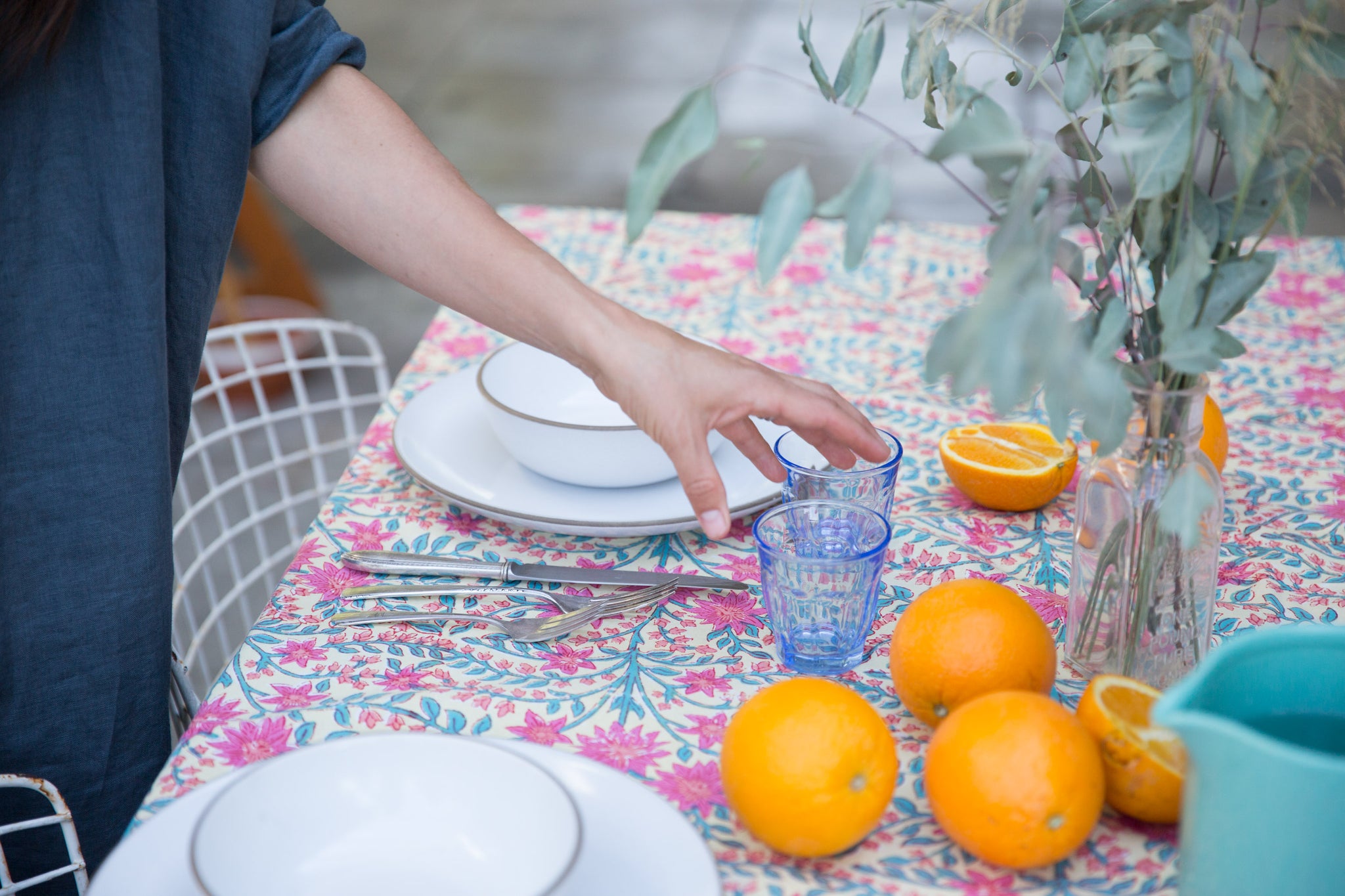pink floral table cloth with oranges and white plates