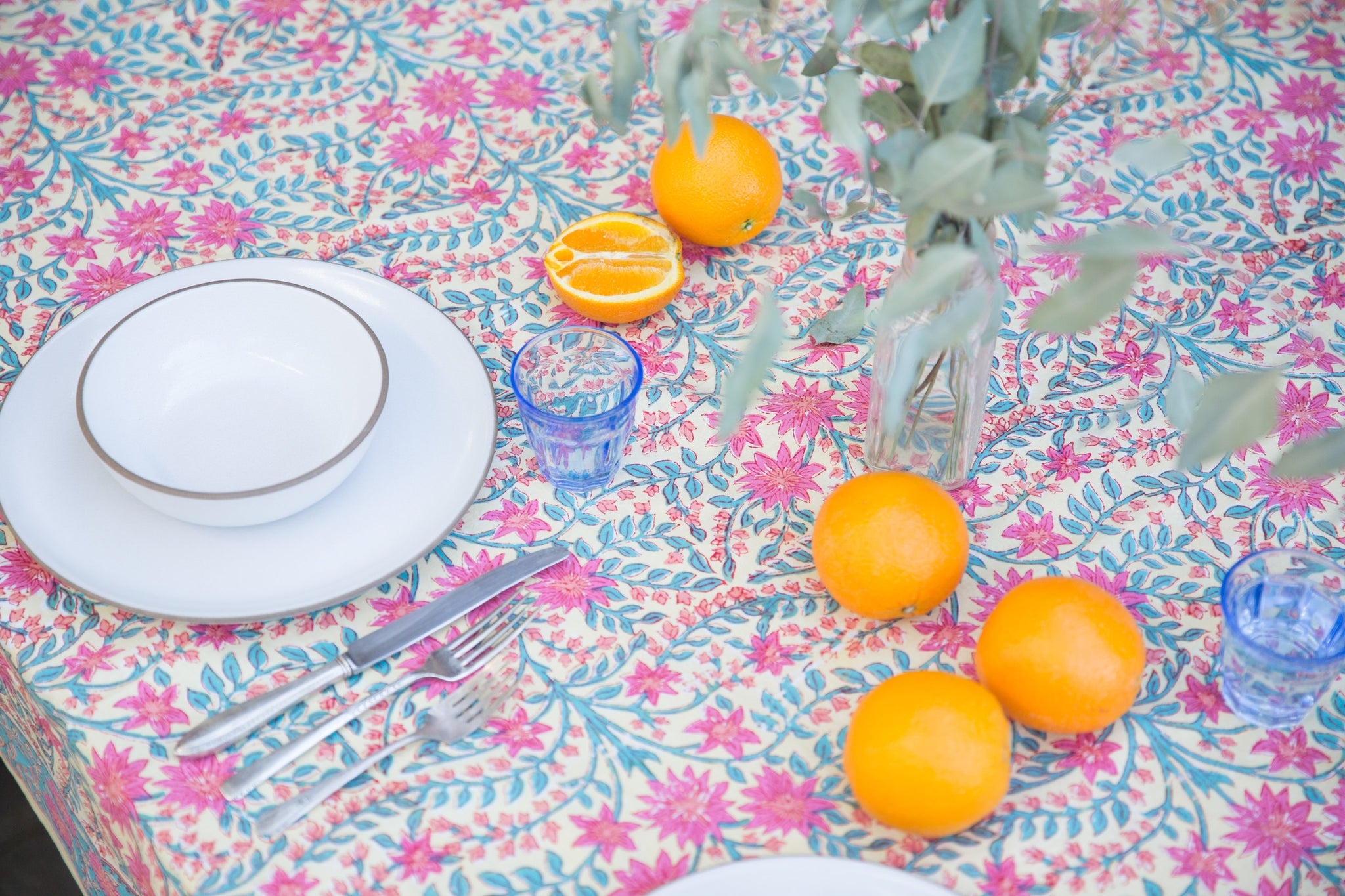 pink floral tablecloth with oranges and white plates