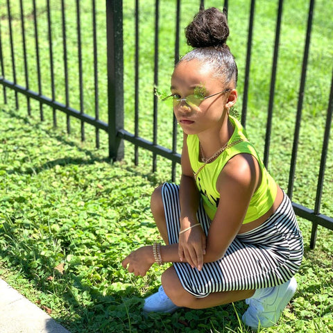 back to school hairstyles: young black girl kneeing with a high bun