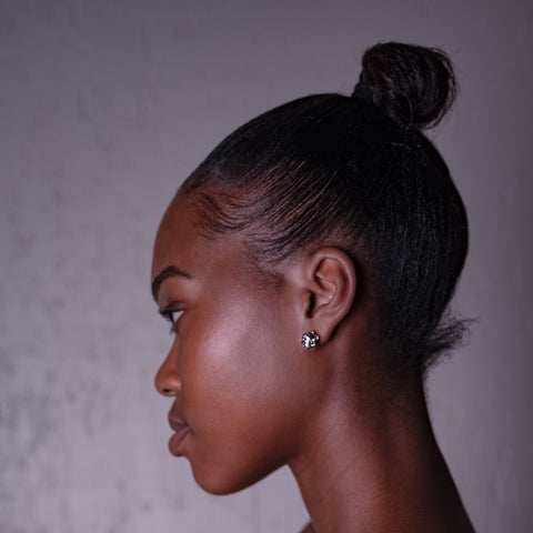 Side view of black woman with straight hair in a high bun looking into the distance