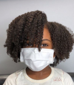 back to school hairstyles: young black girl wearing a mask with a cute wash and go afro