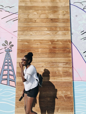 Black woman standing in front of colourful wall in the summer