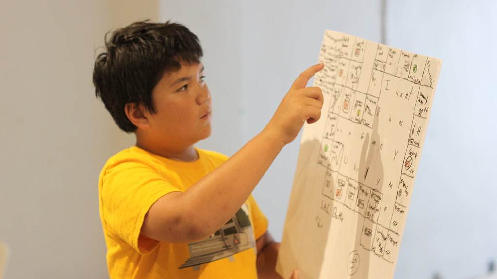Kid explaining his board game design at Little Robot Friends camp