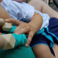 Dieťa, ktoré sa hrá so silikónovými korálmi počas dojčenia