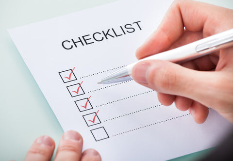 Hands hold a paper reading CHECKLIST with checked boxes