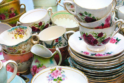 Various flowered teacups and saucers are piled together.