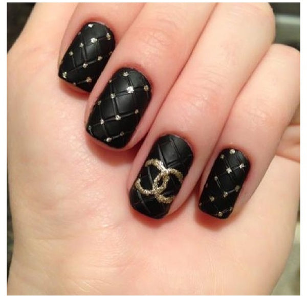 close-in view a nail with quilted nail-art with a black nail color against a dark background