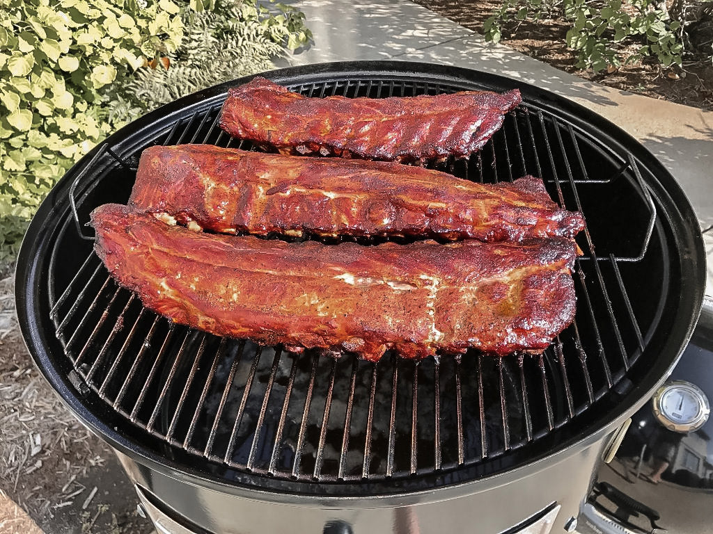 Photo of three racks of ribs cooking on a smoker