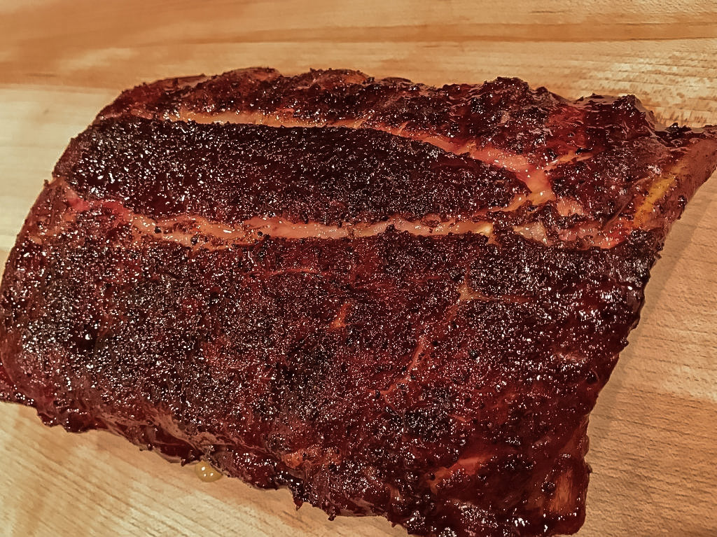Photo of fully cooked rack of ribs covered in dry rub seasoning