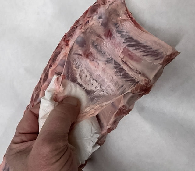 Photo showing how to remove the membrane from the back of a rack of ribs using a paper towel
