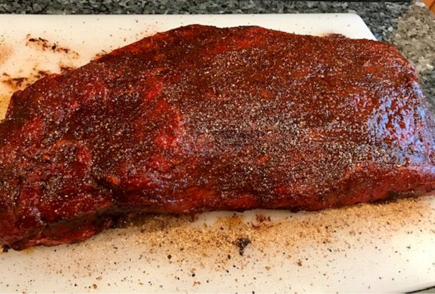 Photo of raw beef brisket covered in barbecue dry rub seasoning