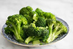 A bow of bright broccoli in a light colored bowl sitting on a table | Bubu Brands 