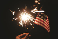 A person holding a sparkler and an american flag | Bubu Brands