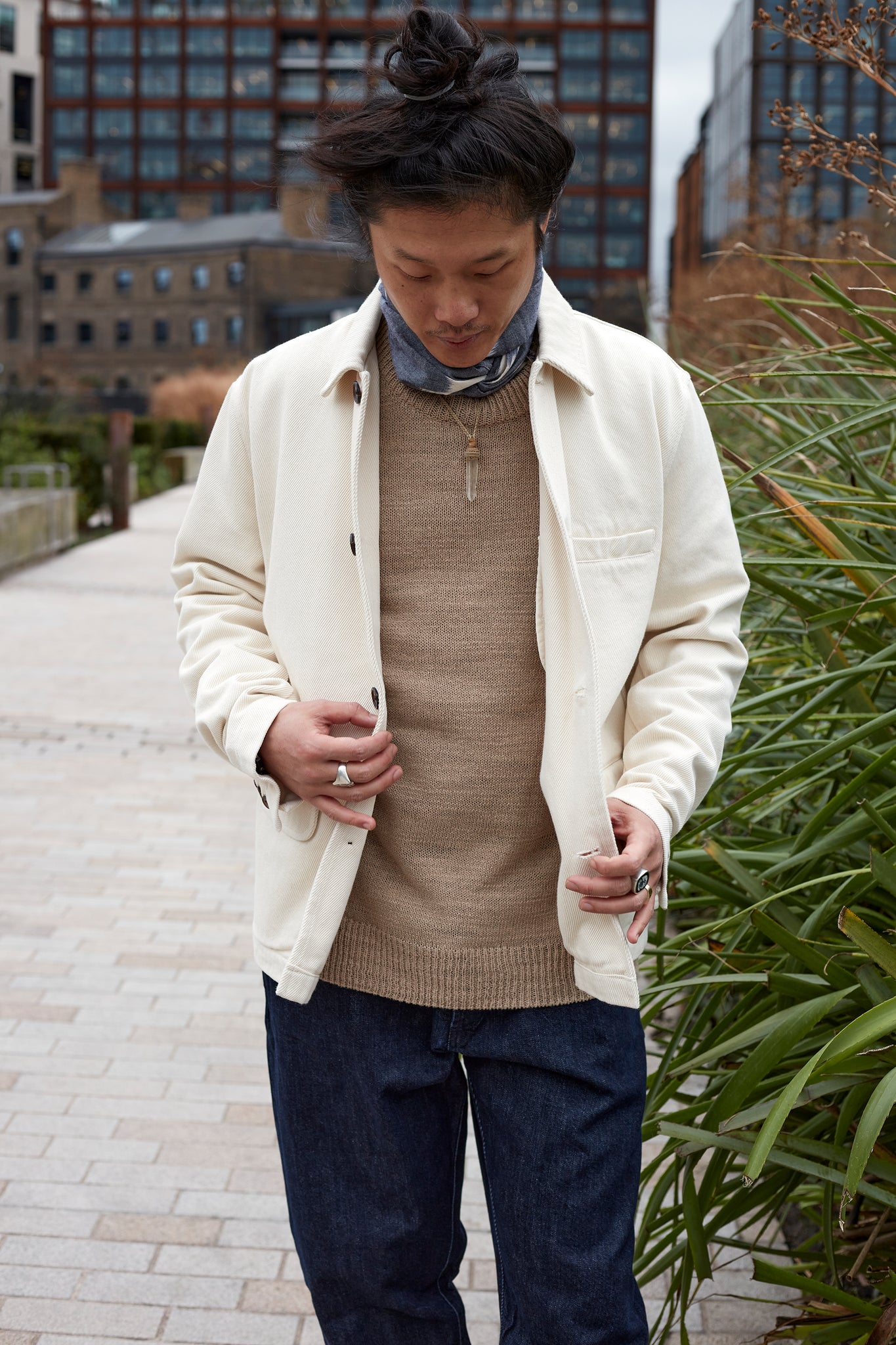 Model wears Universal Works Warmus Jacket with an Ikat Neckerchief and an Elm Loose Crew knit jumper.