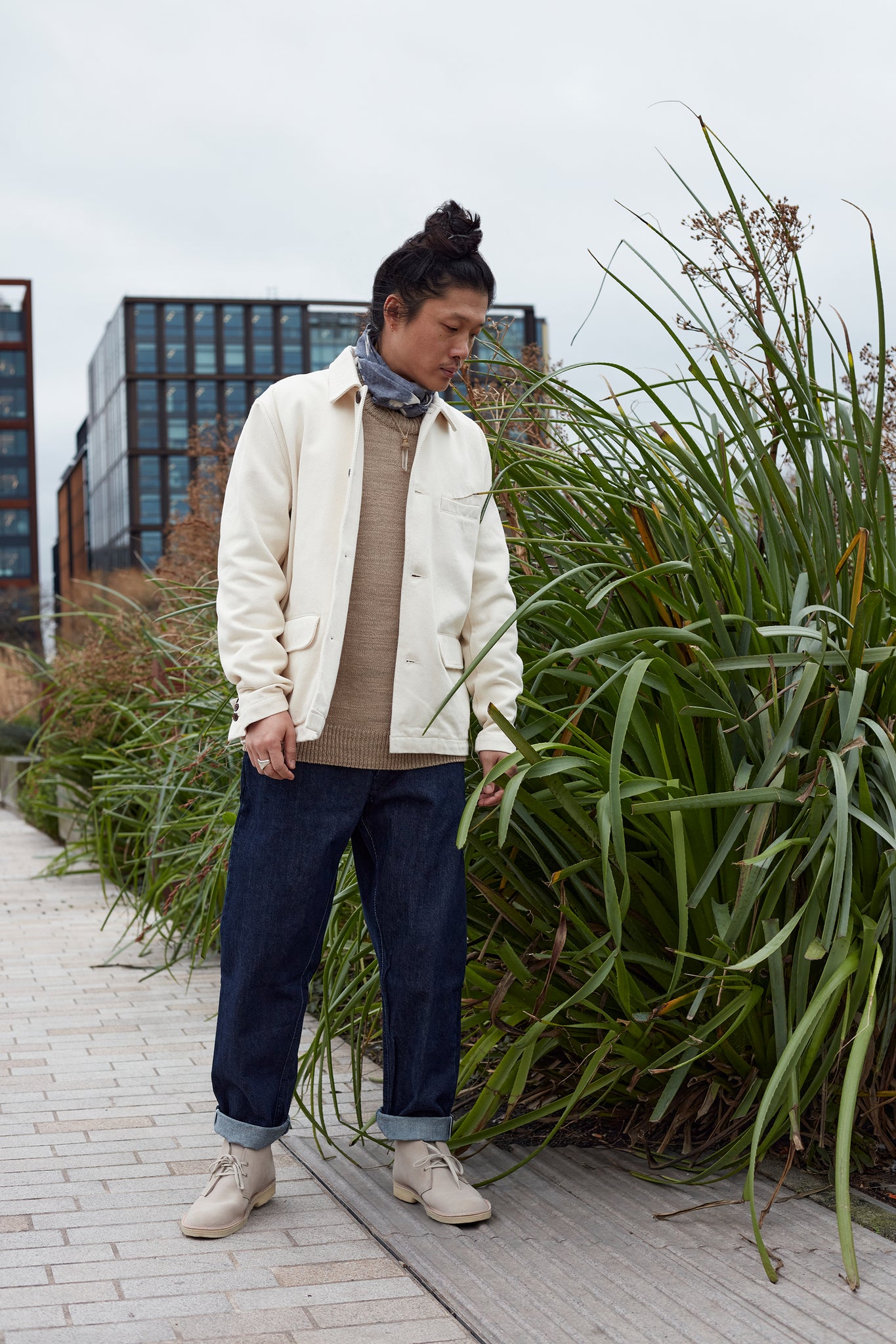 Universal Works Model wears a warmus jacket, knitwear, neckerchief and selvedge military chino.