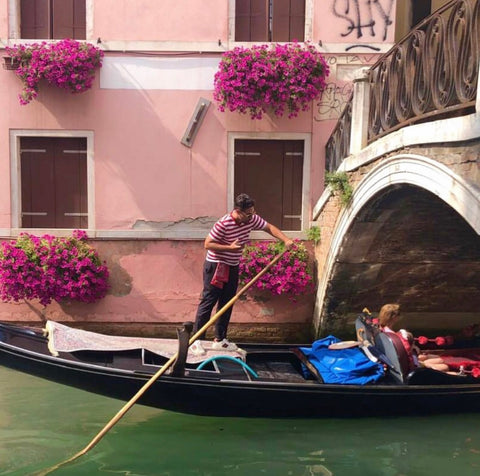 Image of a gondolier in Venice and a pink wall with flowers
