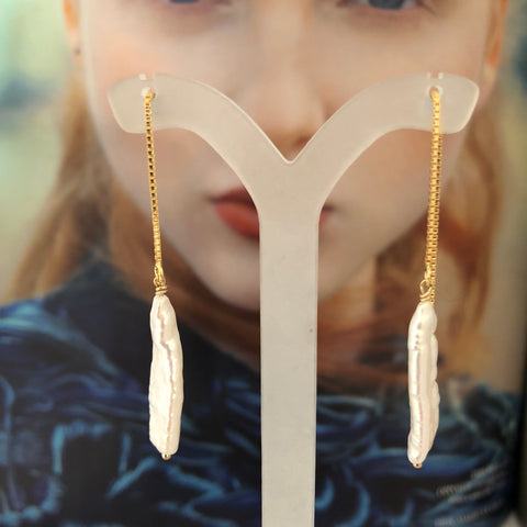 Leoni & Vonk long white pearl gold fill ear thread earrings photographed on a magazine page