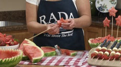 Kristi stringing watermelon stars onto wooden skewers of varying lengths and placing into watermelon bowl