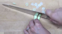 Rada Cutlery's stainless steel French Chef Knife cutting a sprig of green onion