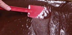 Rada Cutlery's Mixing Spatula spreading a chocolate layer of frosting into the middle of the Blackberry Brownie Cheesecake bars