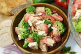 A wooden bowl of our chicken broccoli strawberry bowl with some slices of bread