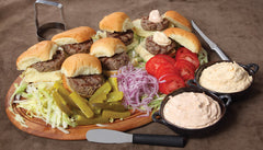 A RADA Party Spreader in in the center of a bowl of coleslaw and eight different hamburgers