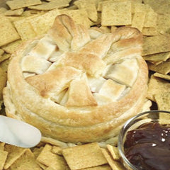 A cheese pastry wheel with a toasted crust topping surrounded by wheat crackers and a small glass bowl of raspberry sauce
