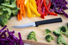 A RADA Heavy Duty Paring Knife on a wooden cutting board next to an assortment of vegetables including broccoli, yellow peppers, red peppers, orange peppers and onions