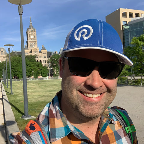 Image of a man (Eric Jacoby) wearing a hat and sunglasses standing 100 yards in front of the Salt Lake City and County Building