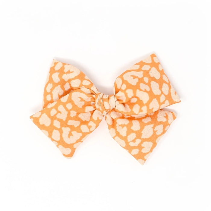 The Kindred Studio orange leopard midi bow against white backdrop